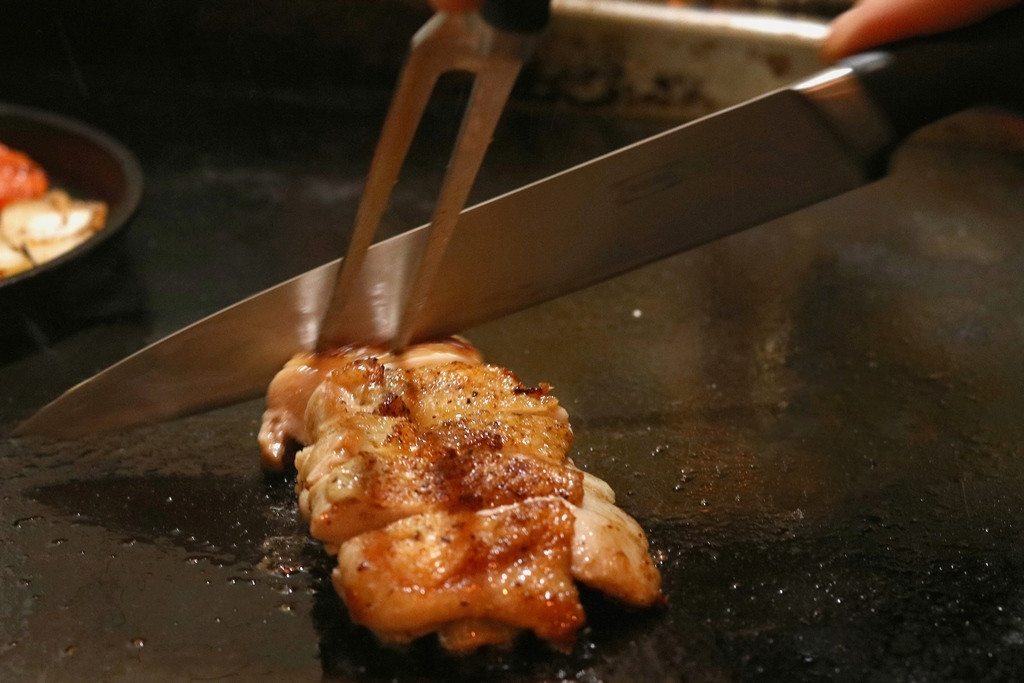 チキングリルを鉄板で切り分けている